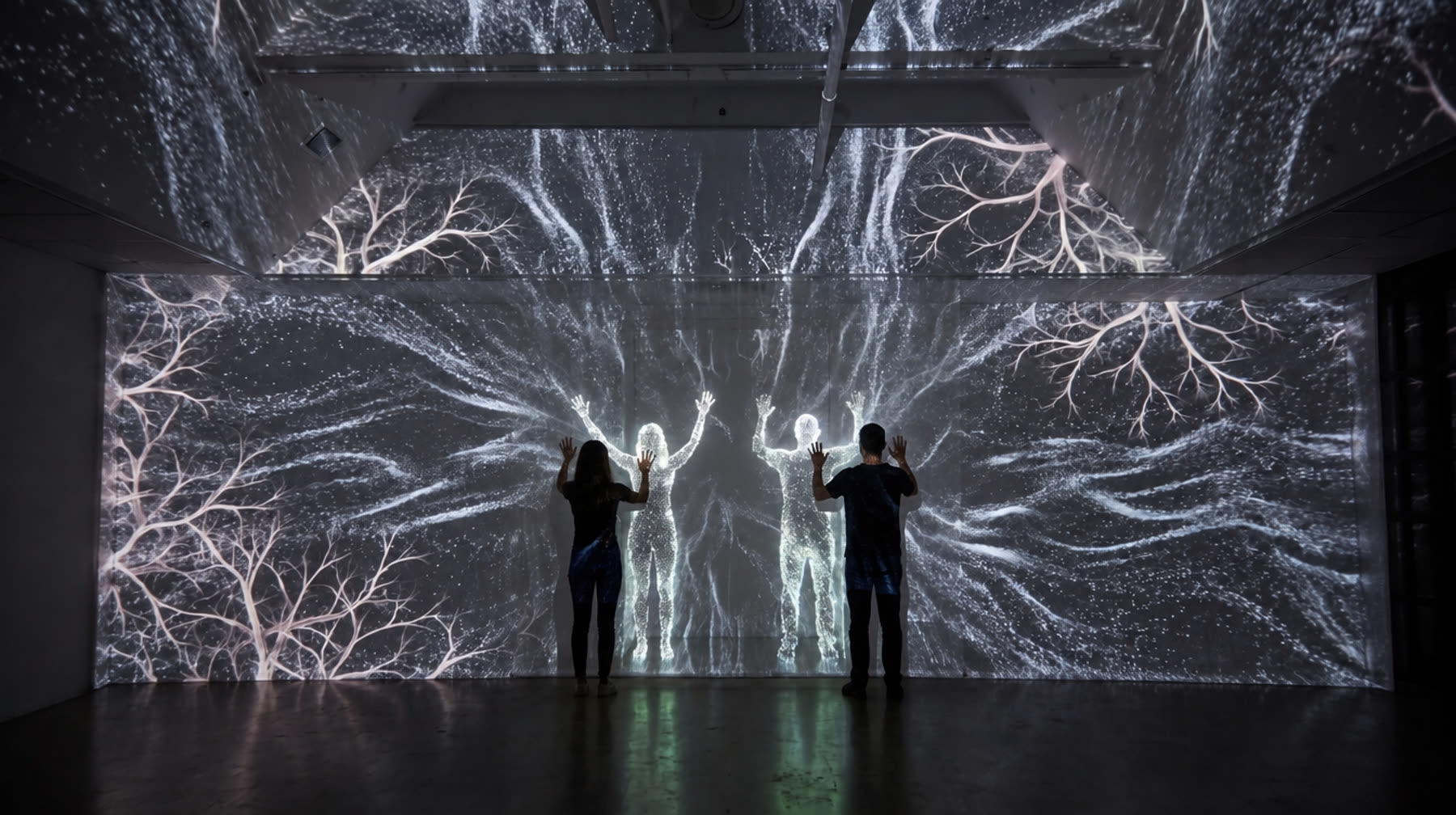 The stage end wall and the beams above it mapped as one image behind a scrim, with visitors mirrored on it as particle figures