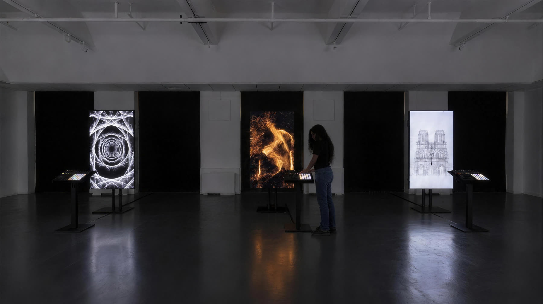 Three portrait displays on stands along the blacked-out window wall, each with a podium and a MIDI controller